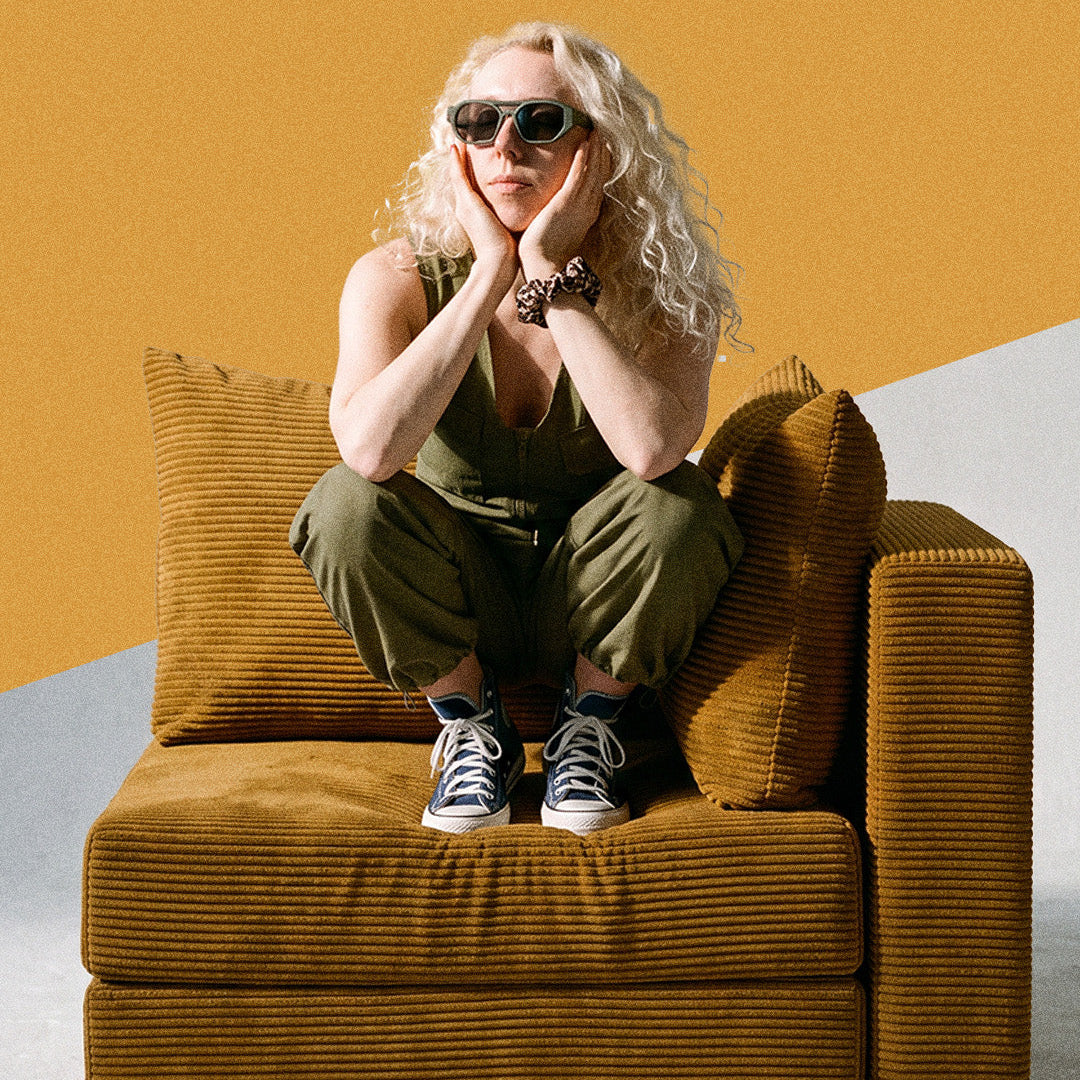 Woman in sunglasses sitting on a mustard corduroy Seesofa foam chair