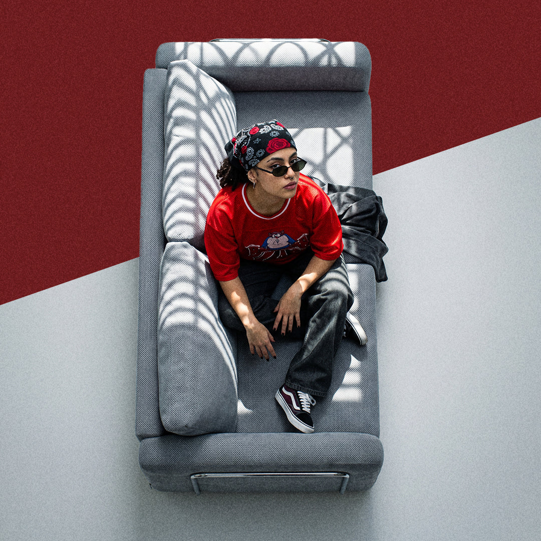 Man in a red jacket lying on a grey Flowy sofa bed, top view
