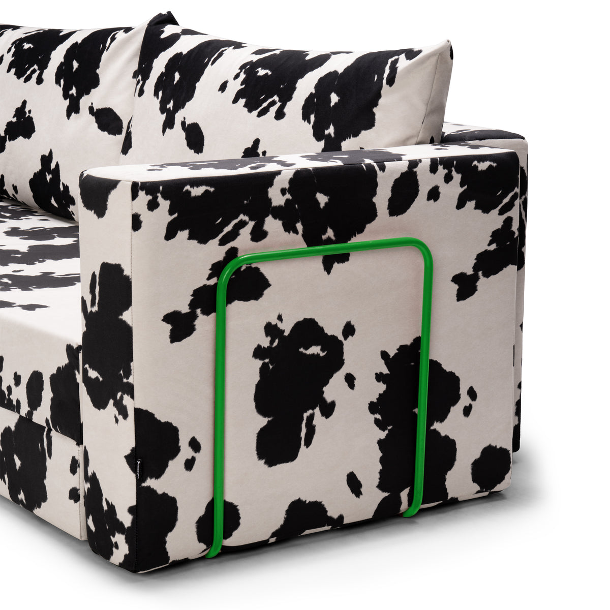 Flow Cow sofa bed in black-and-white cow print fabric with a green metal frame, close-up of the armrest and metal frame
