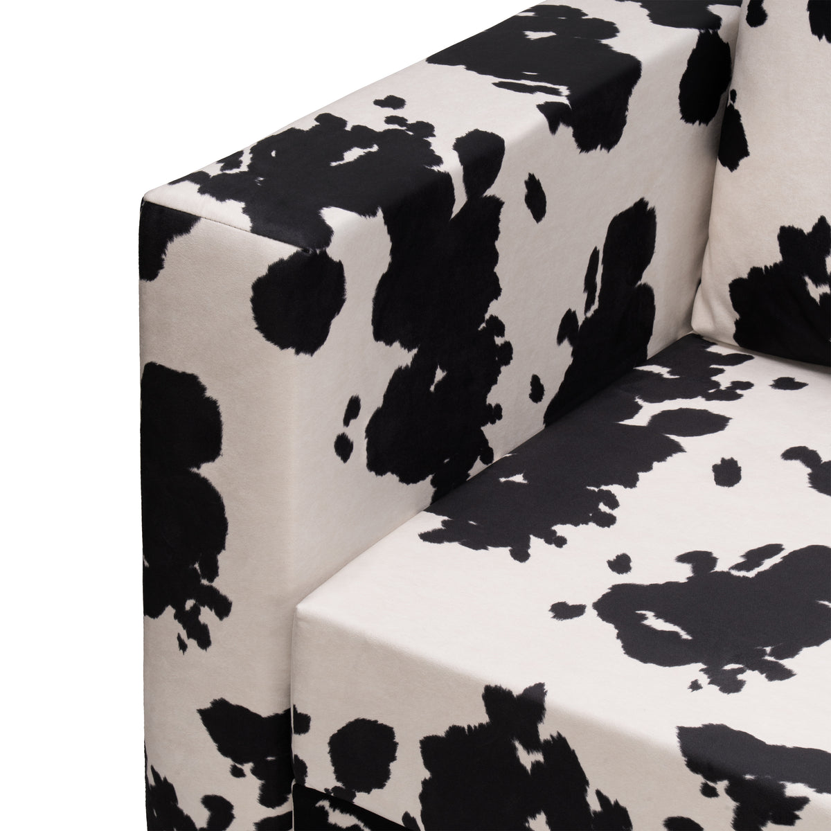 Flow Cow sofa bed in black-and-white cow print fabric with a green metal frame, close-up of the armrest