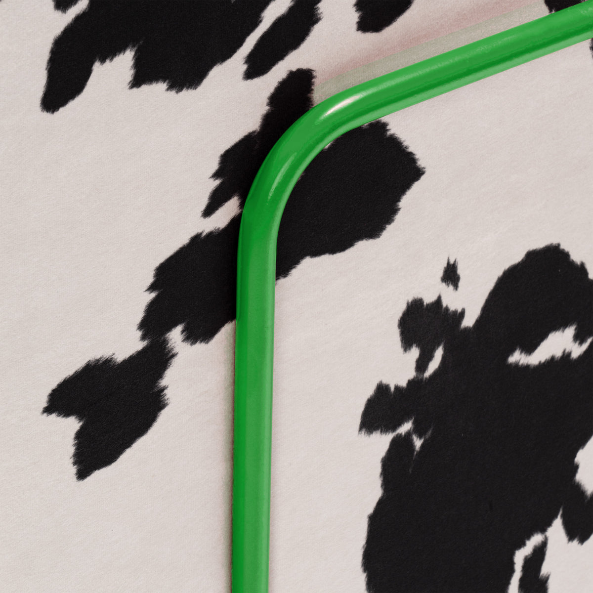 Flow Cow sofa bed in black-and-white cow print fabric with a green metal frame, close-up of the metal frame