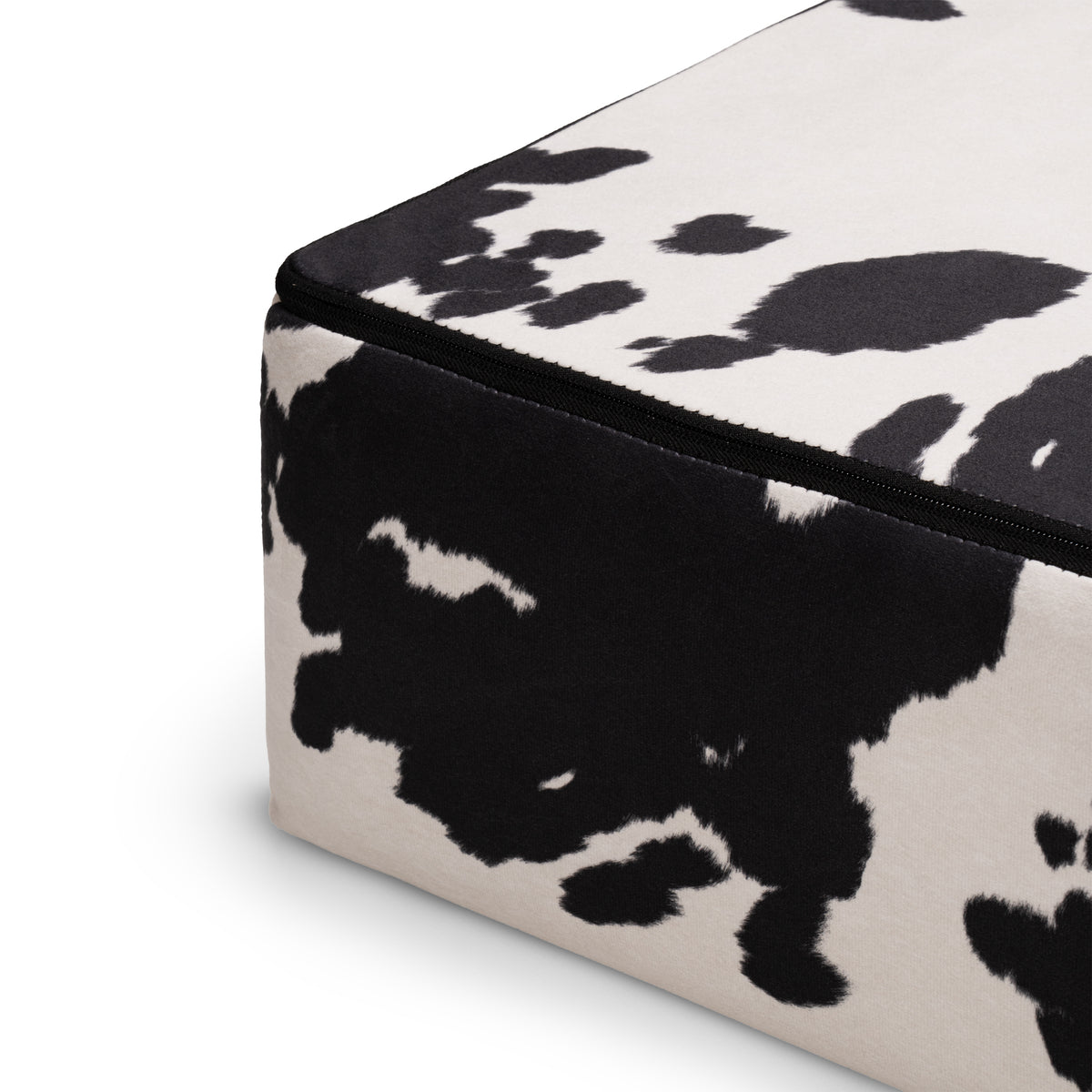 Flow Cow sofa bed in black-and-white cow print fabric with a green metal frame, close-up of the seat cushion edge