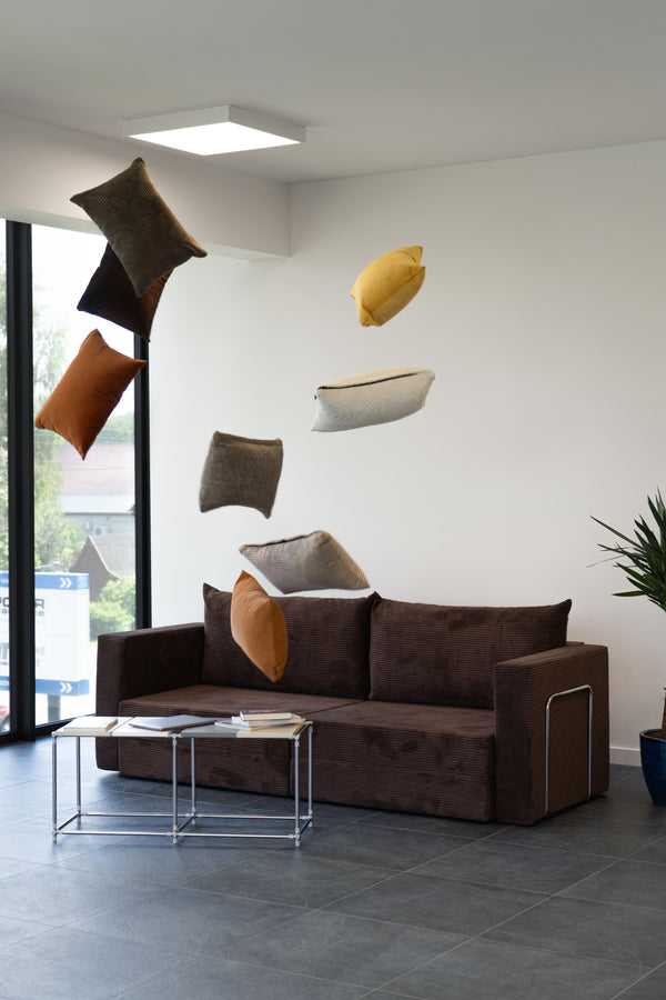 Brown Flow sofa bed with cushions flying in the air