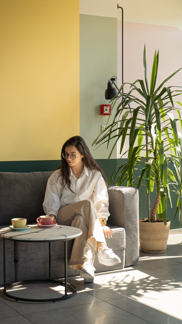 Woman relaxing on a grey Flow chair bed with a coffee