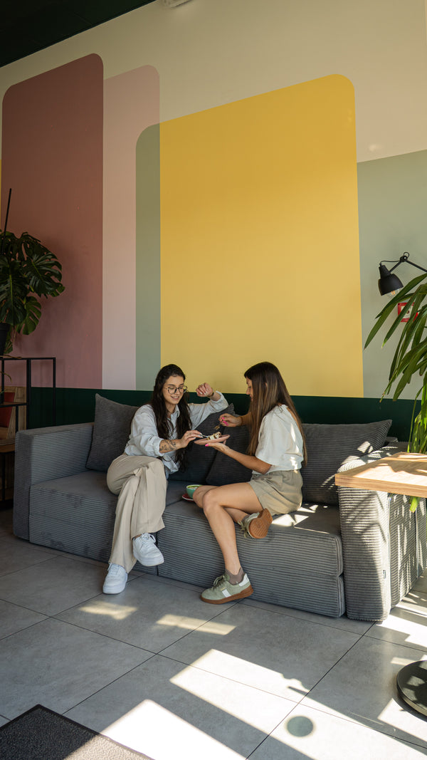 Two women chatting on a grey Flow sofa bed