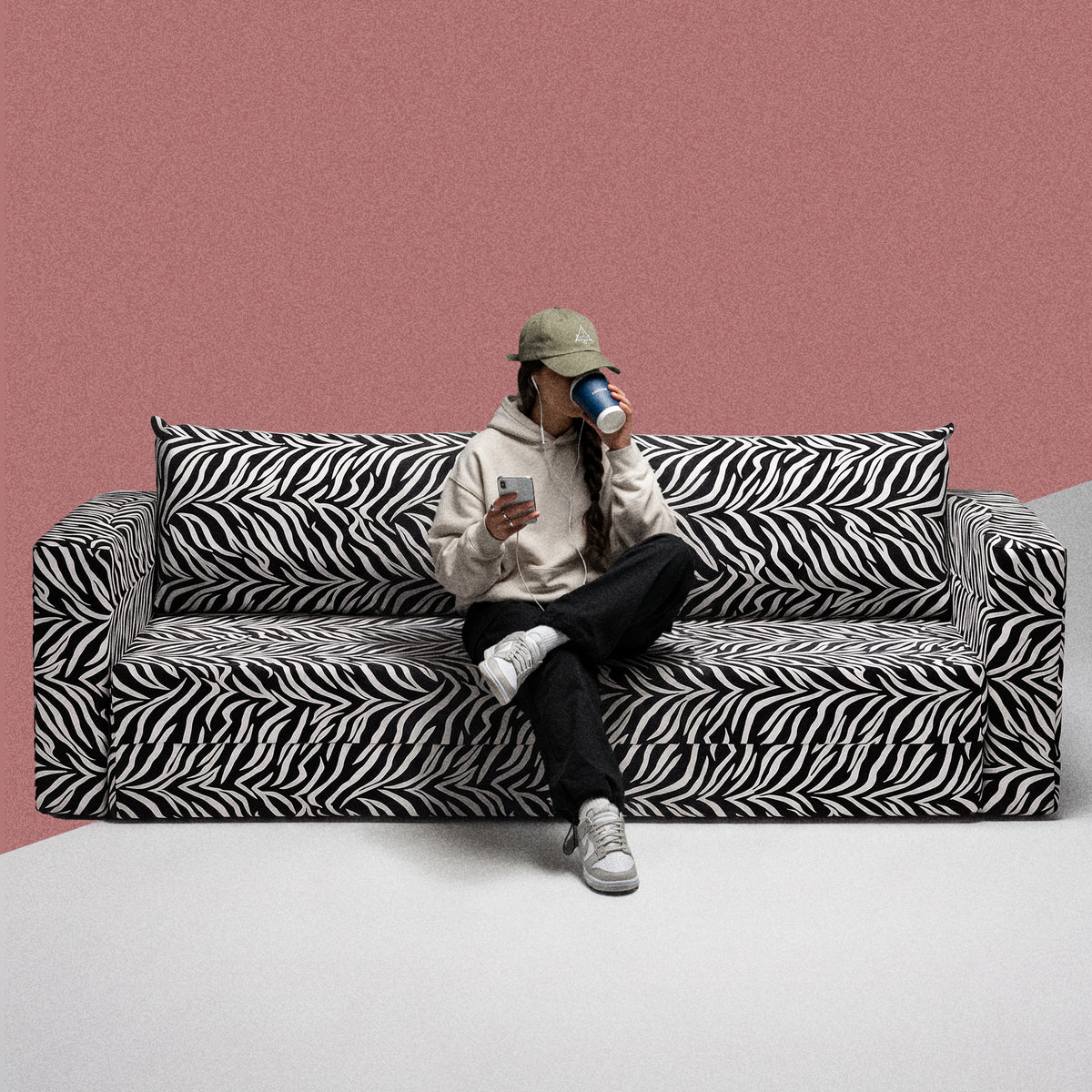 Kvinde sidder på en Flow Zebra sovesofa i sort-hvidt zebramønster